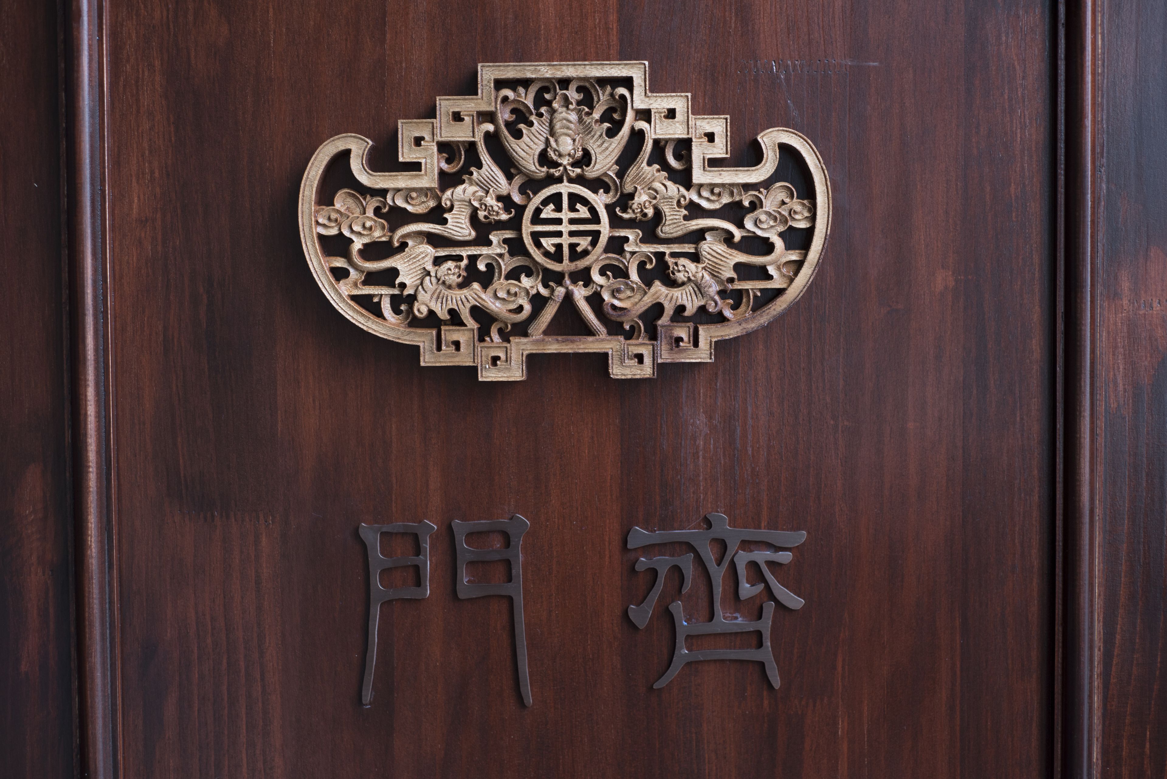 A wooden door with a decorative brass handle and Chinese characters.