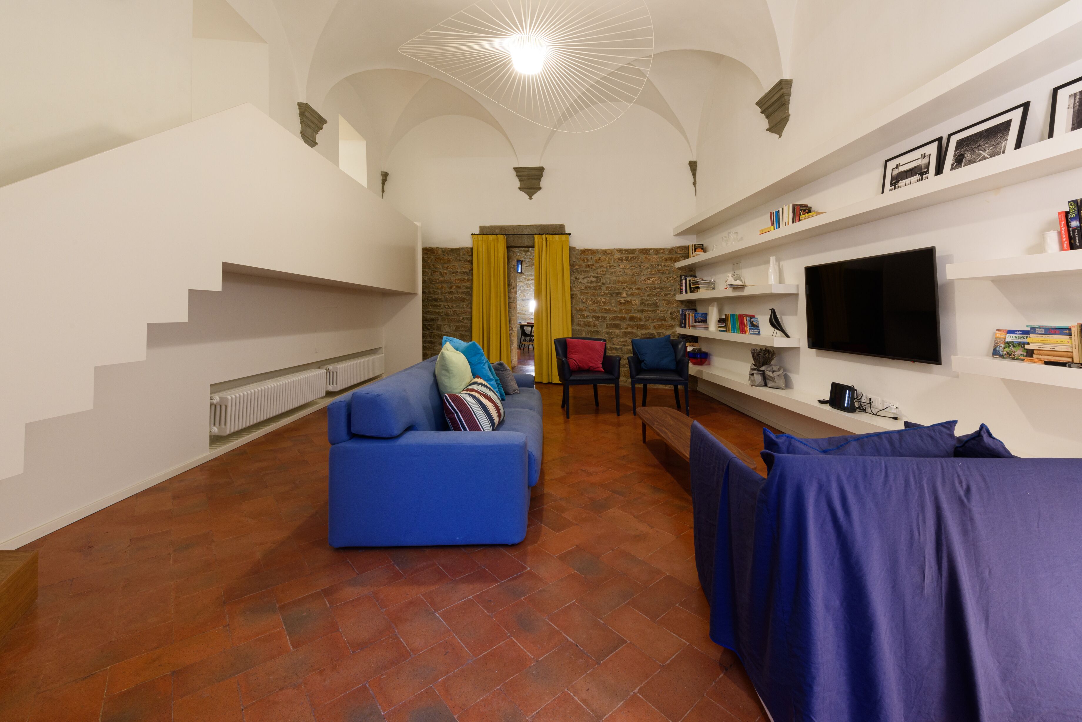A living room with a blue sofa, a television, and a bookshelf.