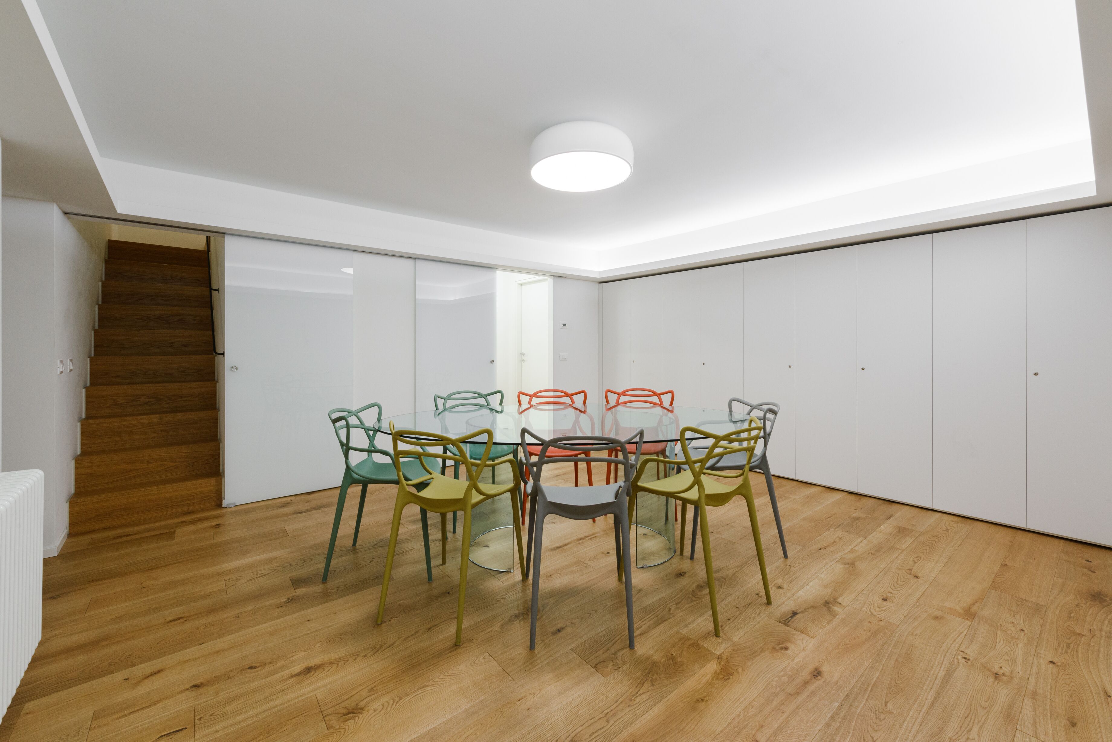 Una habitación moderna con piso de madera, una mesa redonda y sillas coloridas.
