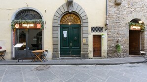 A street with a restaurant named "Cucina in Torre" with a green door and a small outdoor seating area. - 1200 Torre Donati Apartments by Mmega (Florence)