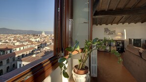 A room with a large window overlooking a cityscape, a potted plant, a sofa, and a radiator. - 1200 Torre Donati Apartments by Mmega (Florence)