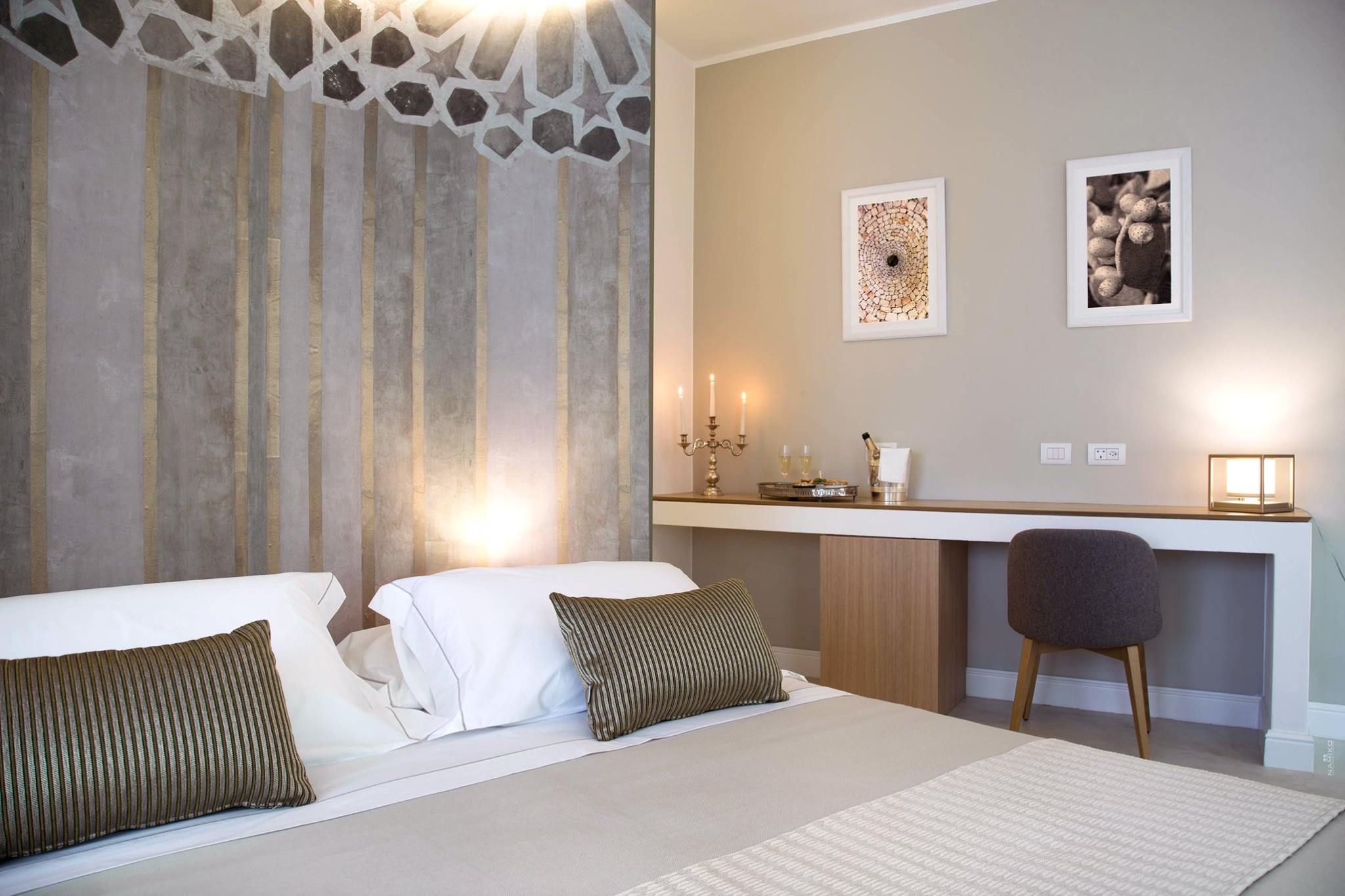 Habitación de hotel con una cama, un escritorio y una silla. Hay dos cuadros en la pared.