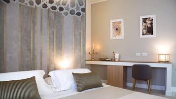 Habitación de hotel con una cama, un escritorio y una silla. Hay dos cuadros en la pared.