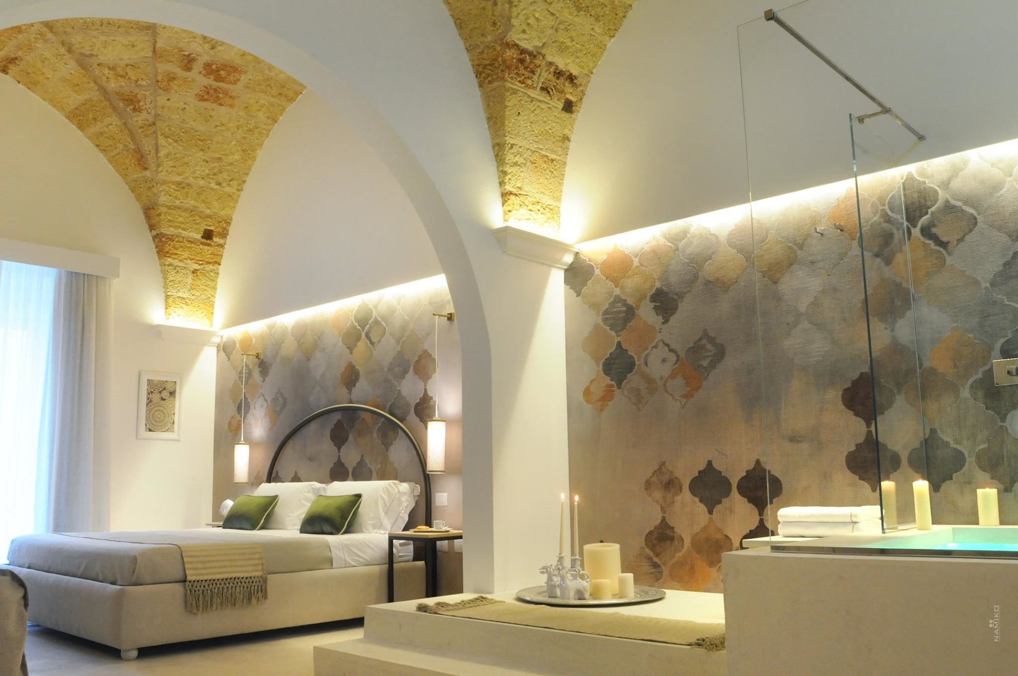 Ein modernes Schlafzimmer mit Bett, Nachttisch, Spiegel und Wand mit geometrischem Muster.