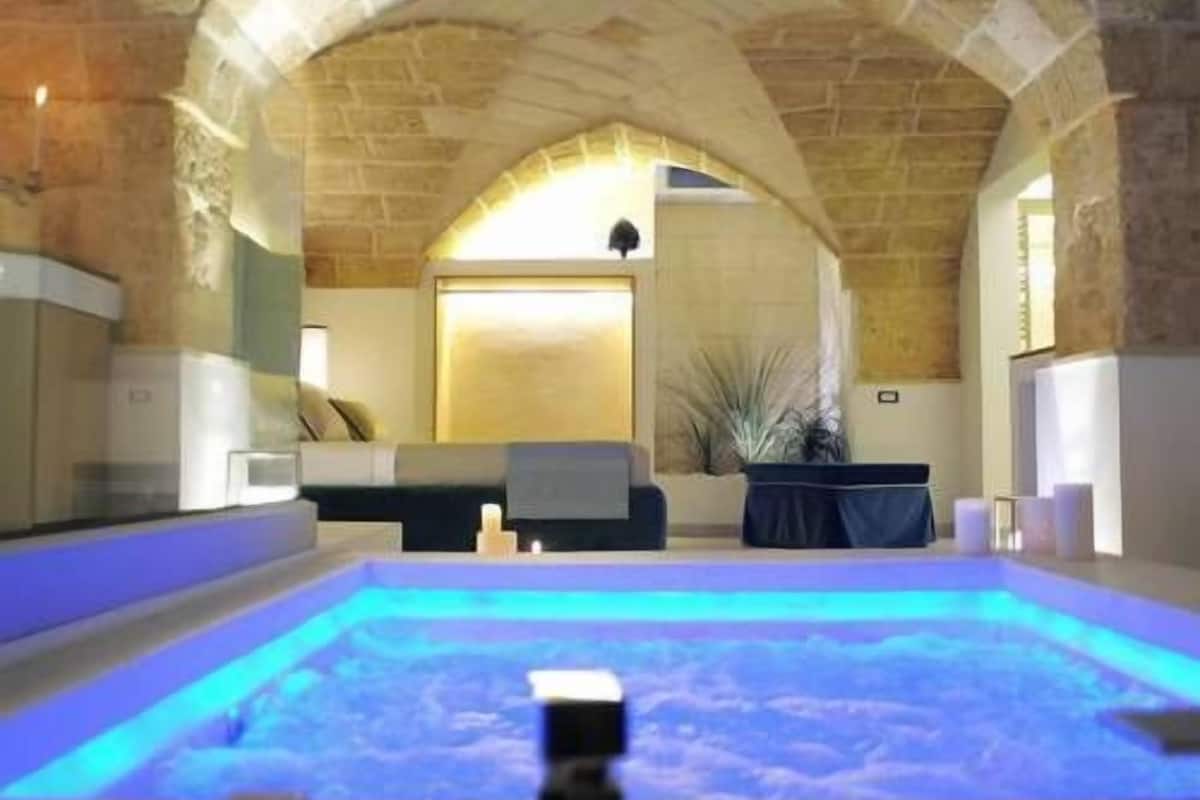 A spa area with a hot tub, stone arches, and a seating area with a view of the room.