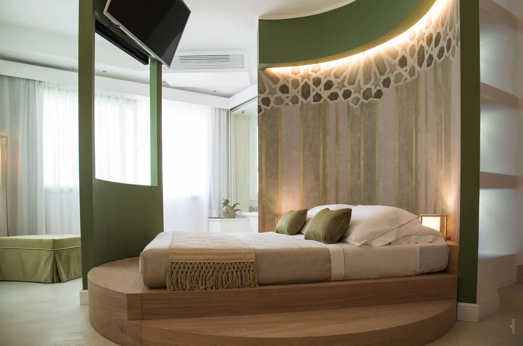 Un dormitorio moderno con una cama curvada, un televisor de pantalla plana en la pared y un panel decorativo.