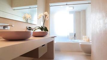 A modern bathroom with a large sink, a mirror, and a bathtub.