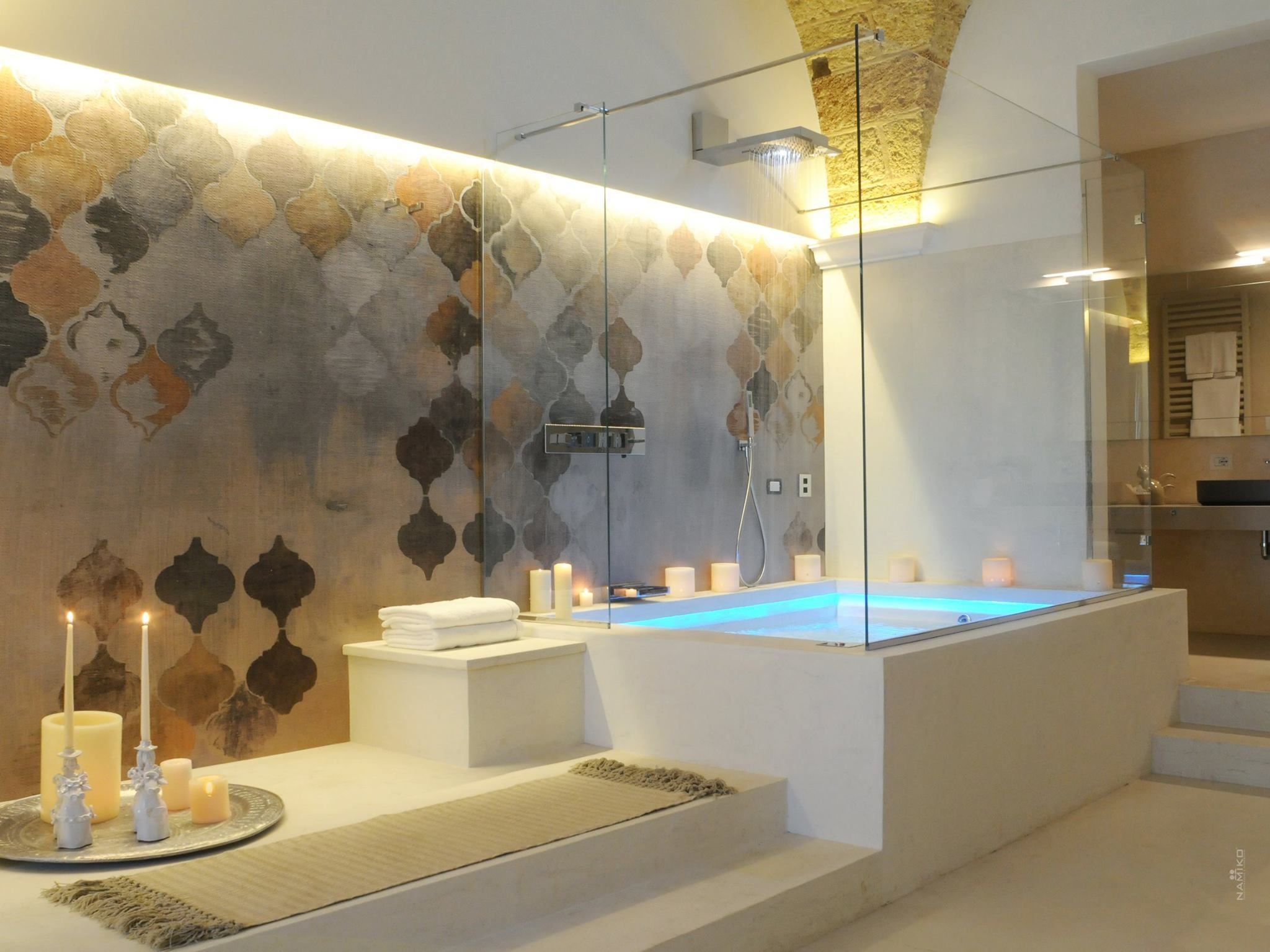 Ein modernes Badezimmer mit einem gläsernen Whirlpool, einer Wand mit Steinmusterung und einem minimalistischen Design.