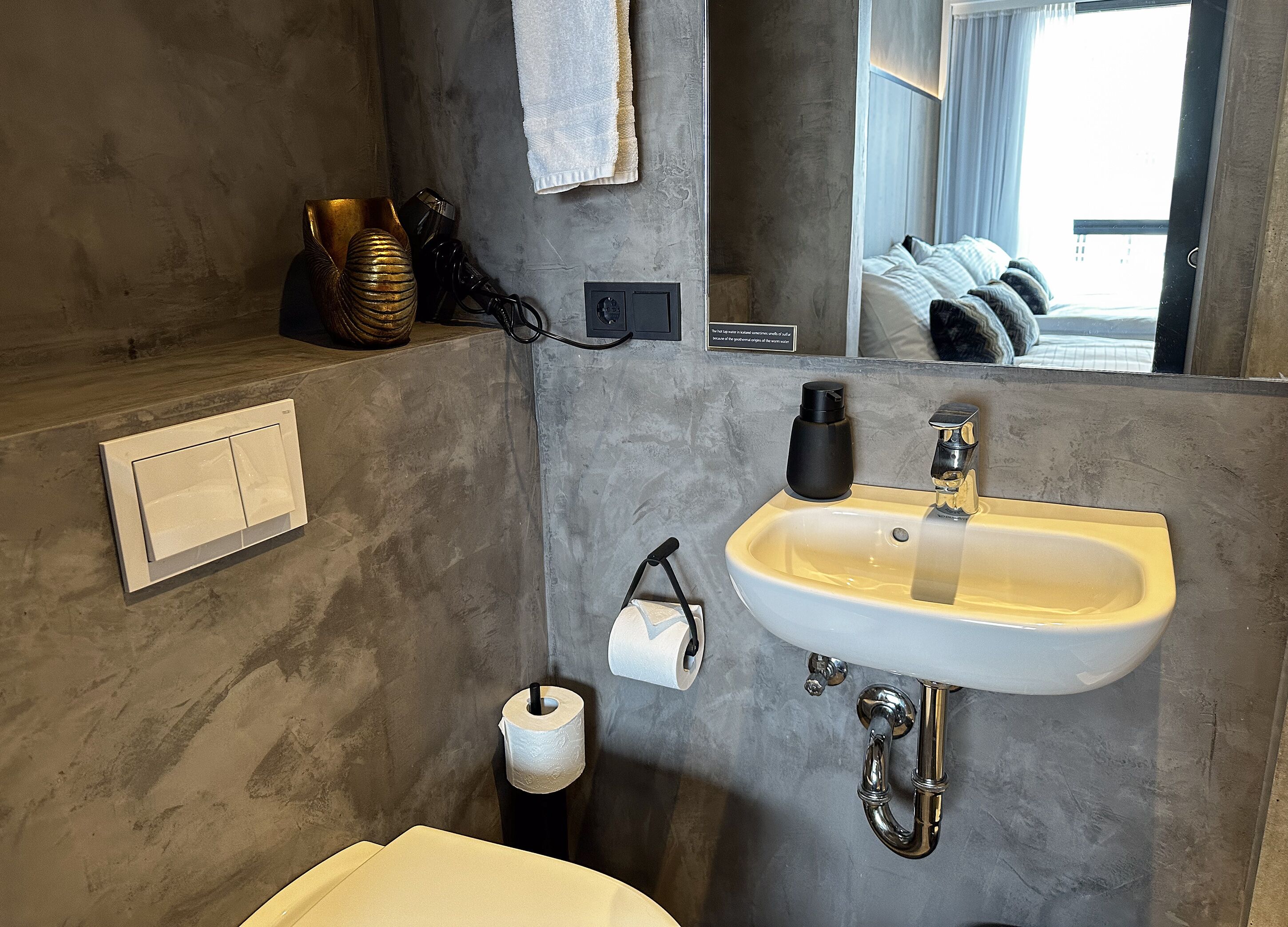 A bathroom with a sink, mirror, towel rack, and a toilet.