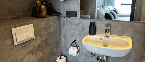 A bathroom with a sink, mirror, towel rack, and a toilet.