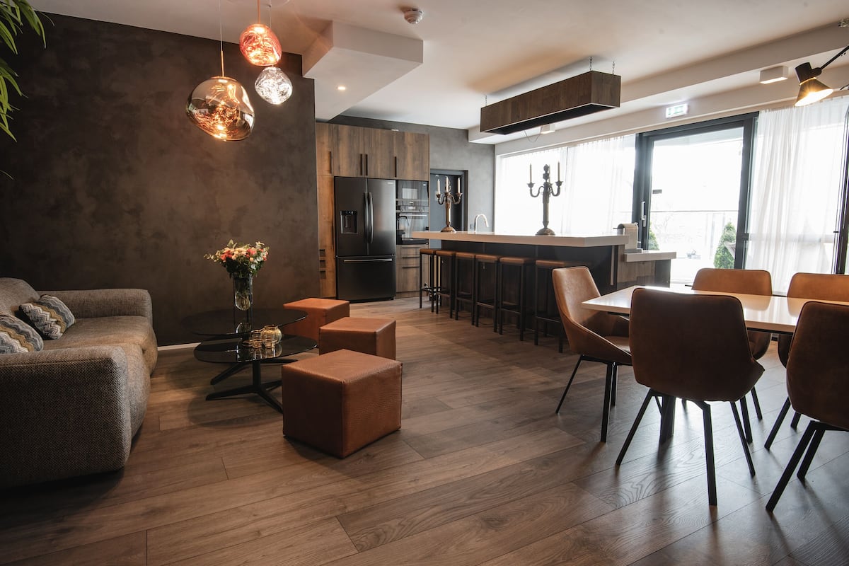 A modern kitchen with dark wood cabinets, a central island, and a dining area with a table and chairs.