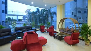 A modern lobby with a mix of seating options, large windows offering a view of the cityscape, and a clean, contemporary design. - Siam Golden Place Suvarnabhumi (Bangkok)