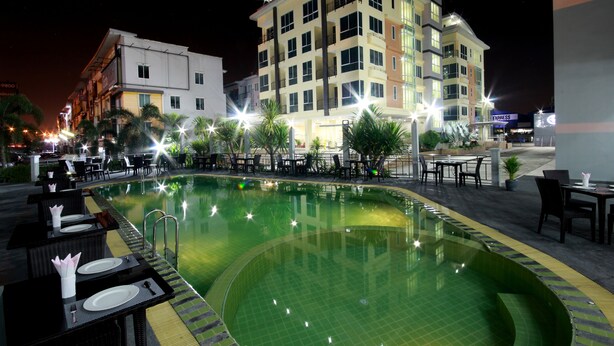 A nighttime view of a hotel with a swimming pool, outdoor seating, and a multi-story building with balconies. - Siam Golden Place Suvarnabhumi (Bangkok)