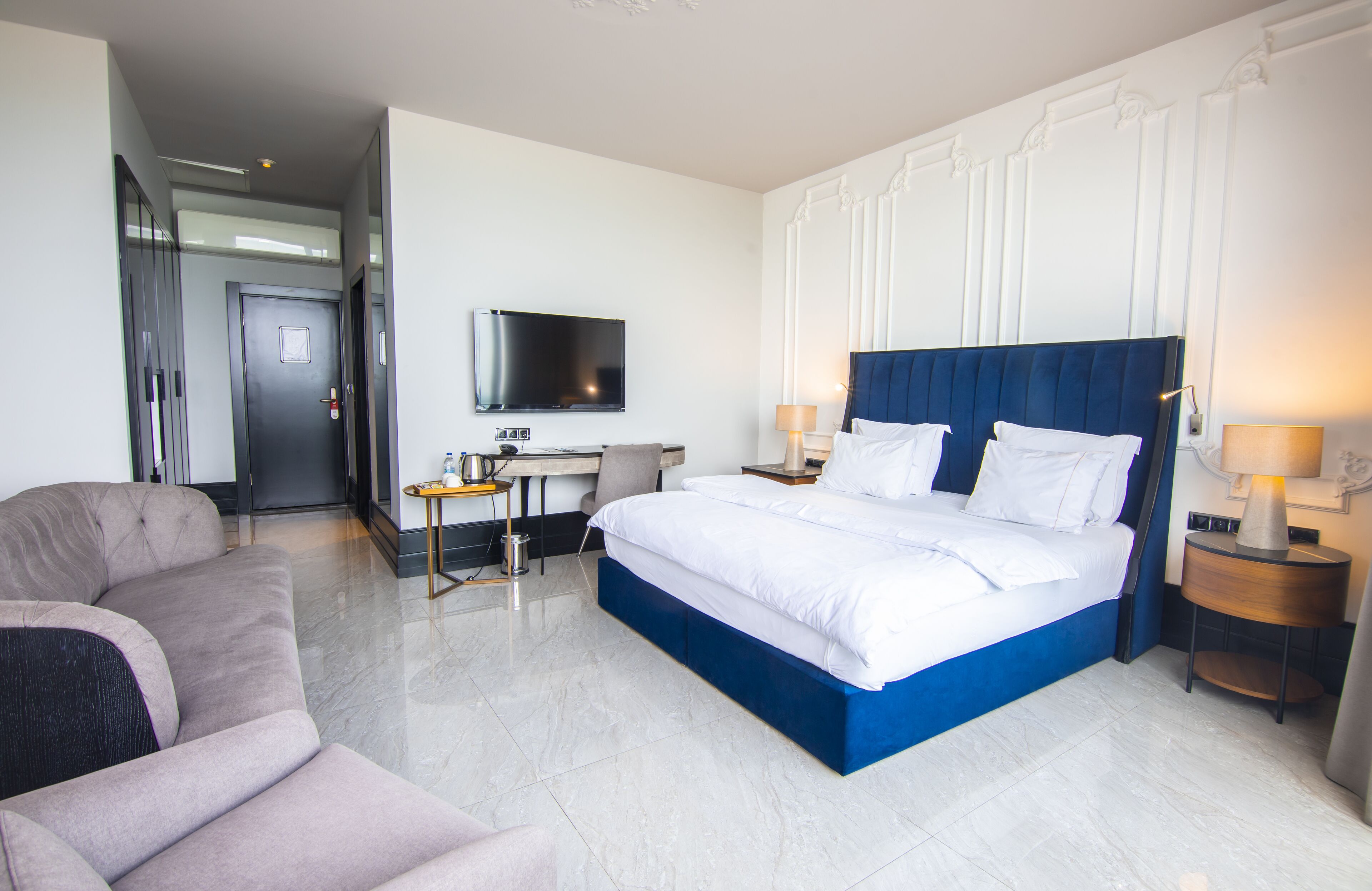 Una habitación de hotel con una cama grande, un escritorio, un televisor y un sofá.