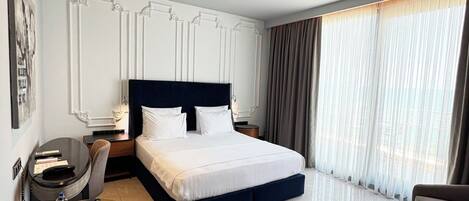 Una habitación de hotel moderna con una cama grande, un escritorio, una silla y un sofá.