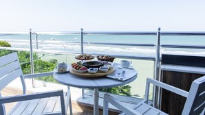 Balcón con mesa lista para el desayuno con vista a la playa.