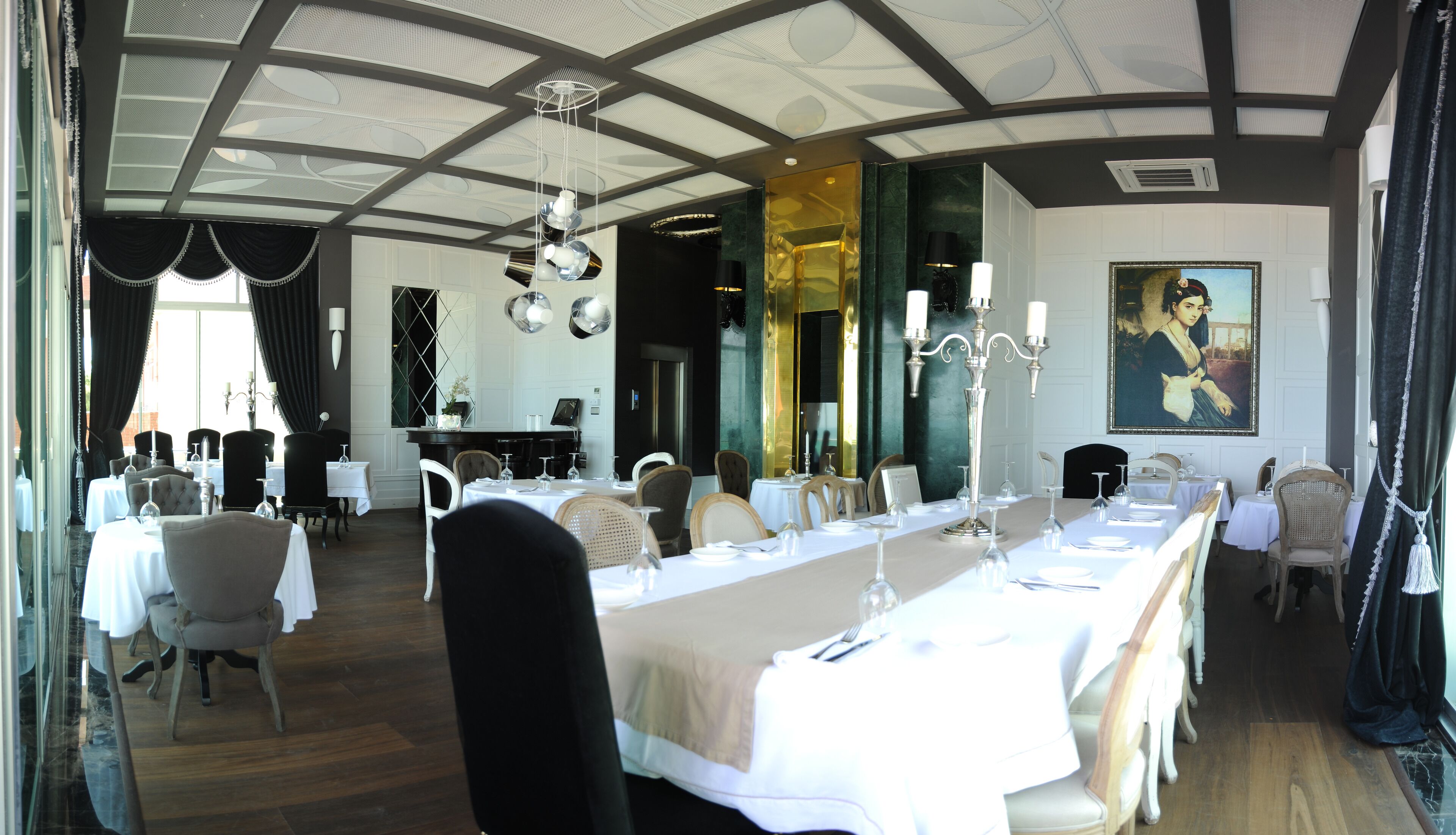 A formal dining room with long tables, chairs, and a high ceiling with skylights.