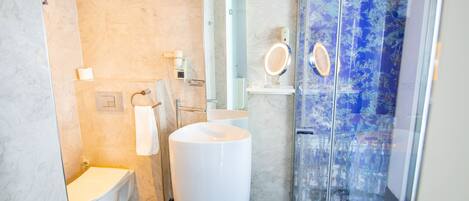 Ein modernes Badezimmer mit Toilette, Bidet, großem Waschbecken und einer Duschkabine aus Glas.
