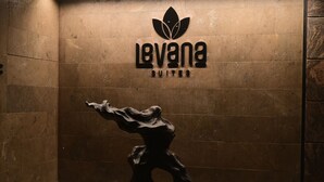 A statue of a figure in a dynamic pose, a logo for 'Levana Suites', and a textured wall. - Levana Suites (Lucknow)