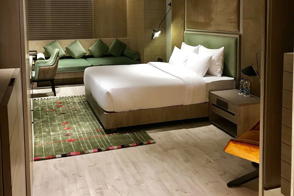 A modern bedroom with a large bed, a bedside table, a chair, and a green sofa.