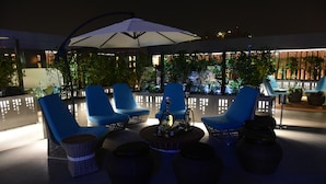 An outdoor seating area with blue chairs, a central table with a hookah, and wicker baskets. - Levana Suites (Lucknow)