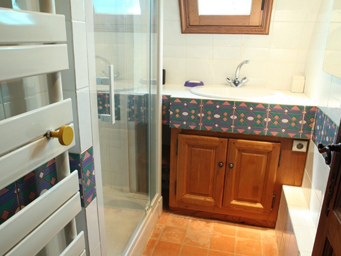 A bathroom with a shower, a sink, and wooden cabinets.