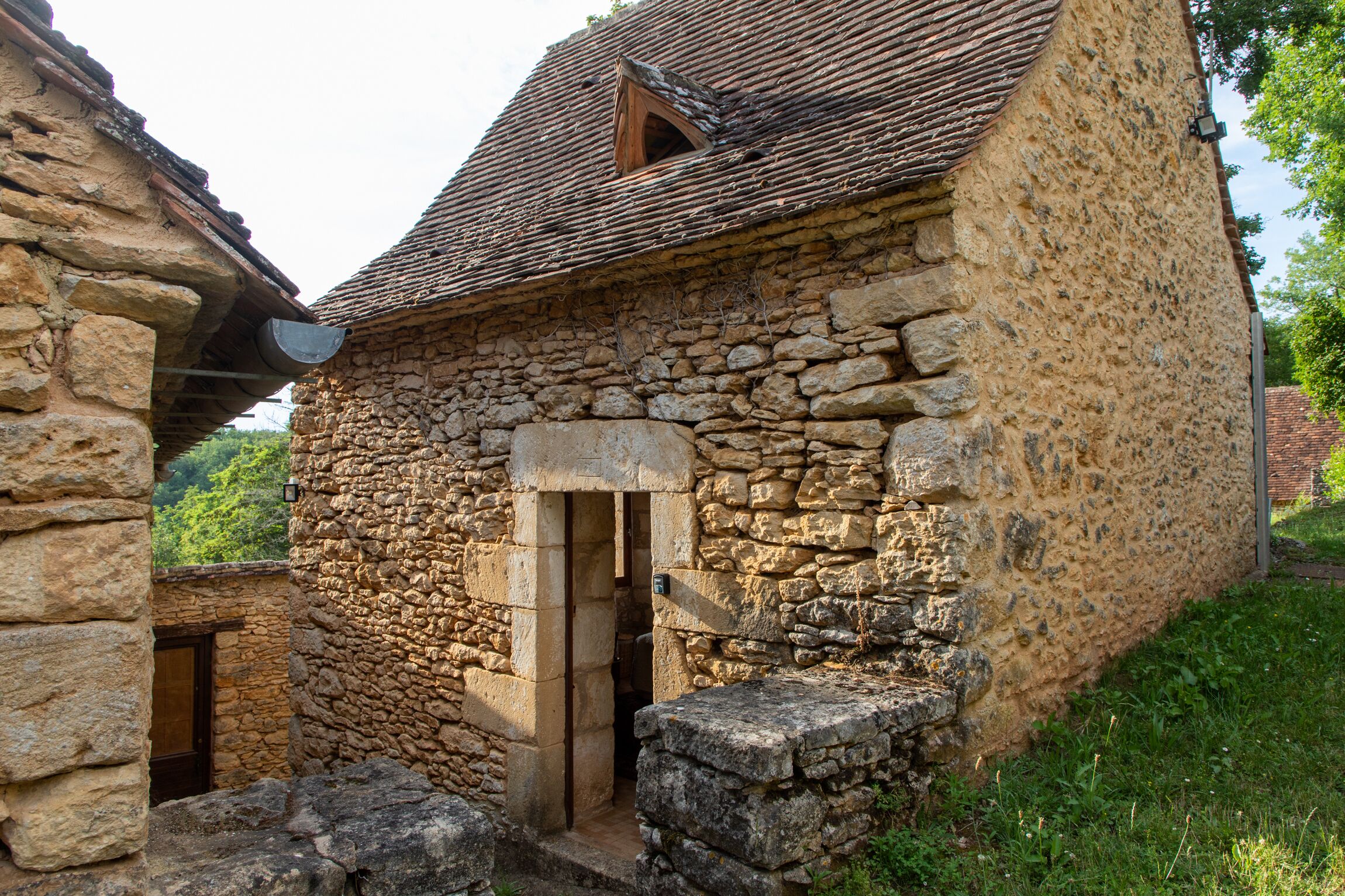 Un bâtiment en pierre doté d’un toit à pente traditionnelle et d’une petite fenêtre.