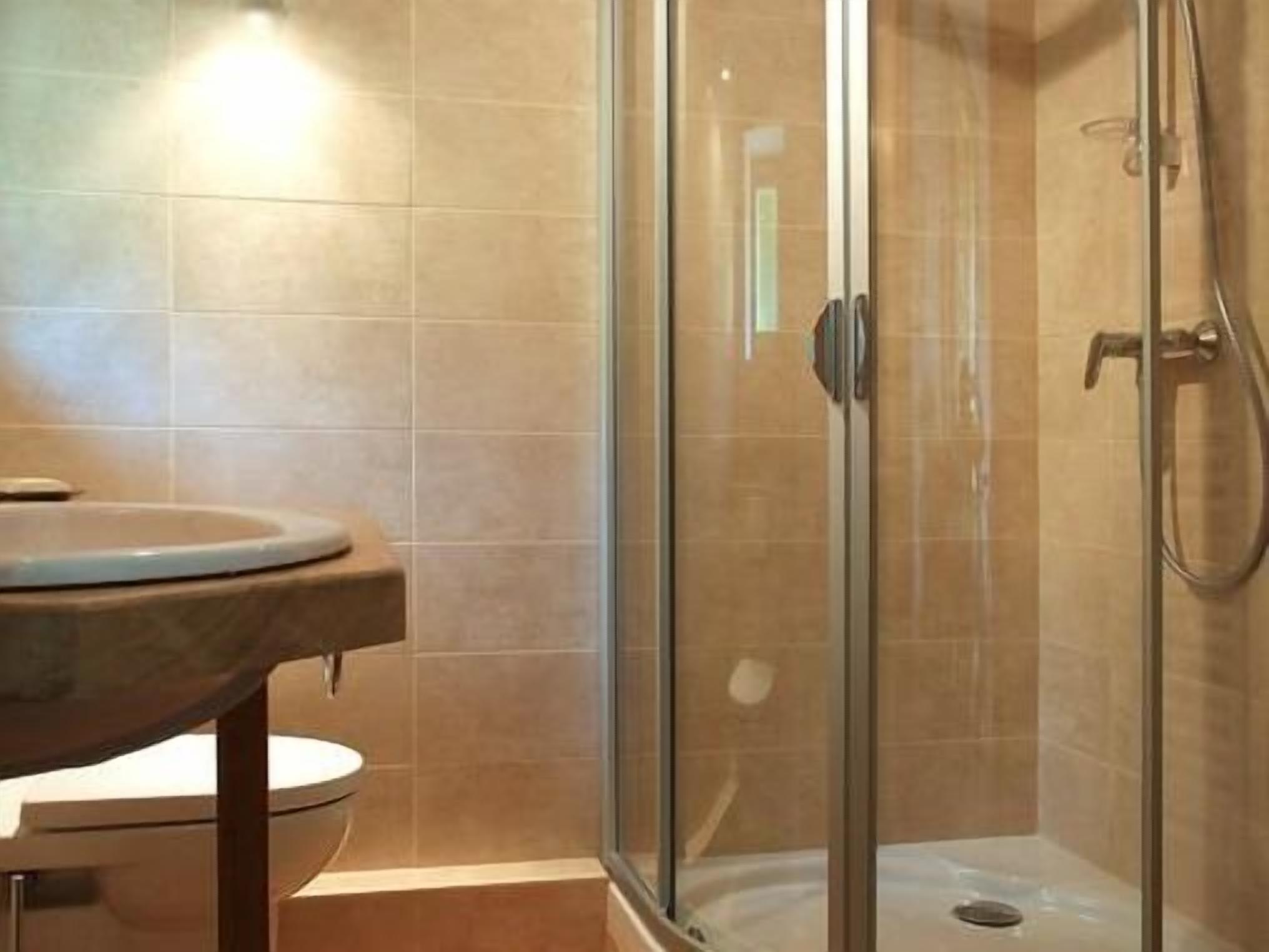 A bathroom with a toilet, a shower enclosure, and tiled walls.