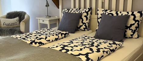 A bedroom with a bed, a map on the wall, and a chair with a cushion.