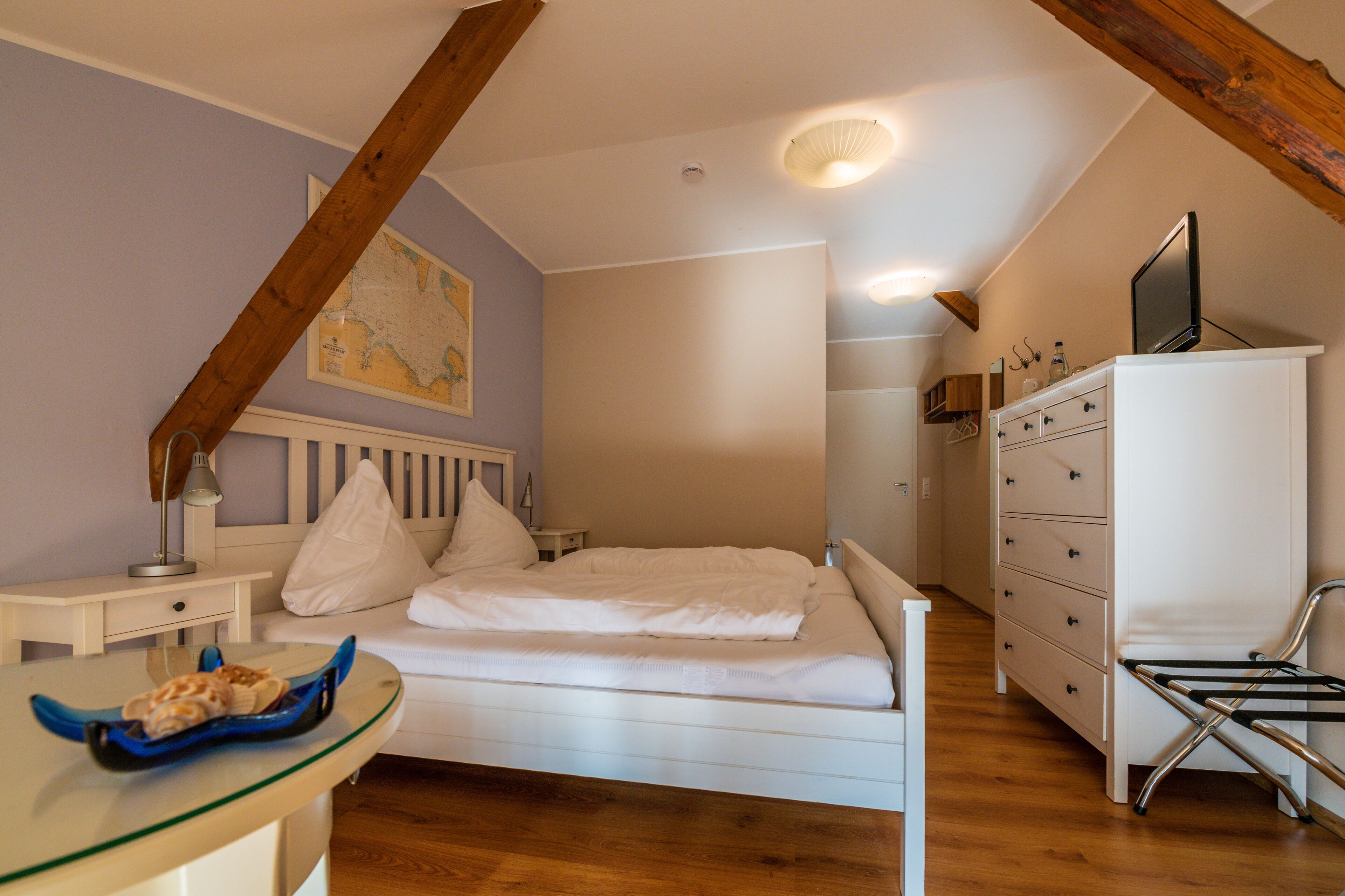 Un dormitorio con cama, cómoda, escritorio y un mapa en la pared.