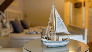 A model sailboat on a glass table in a room with a staircase and a sofa in the background. - Kleines Landhotel Rehedyk (Sankt Michaelisdonn)