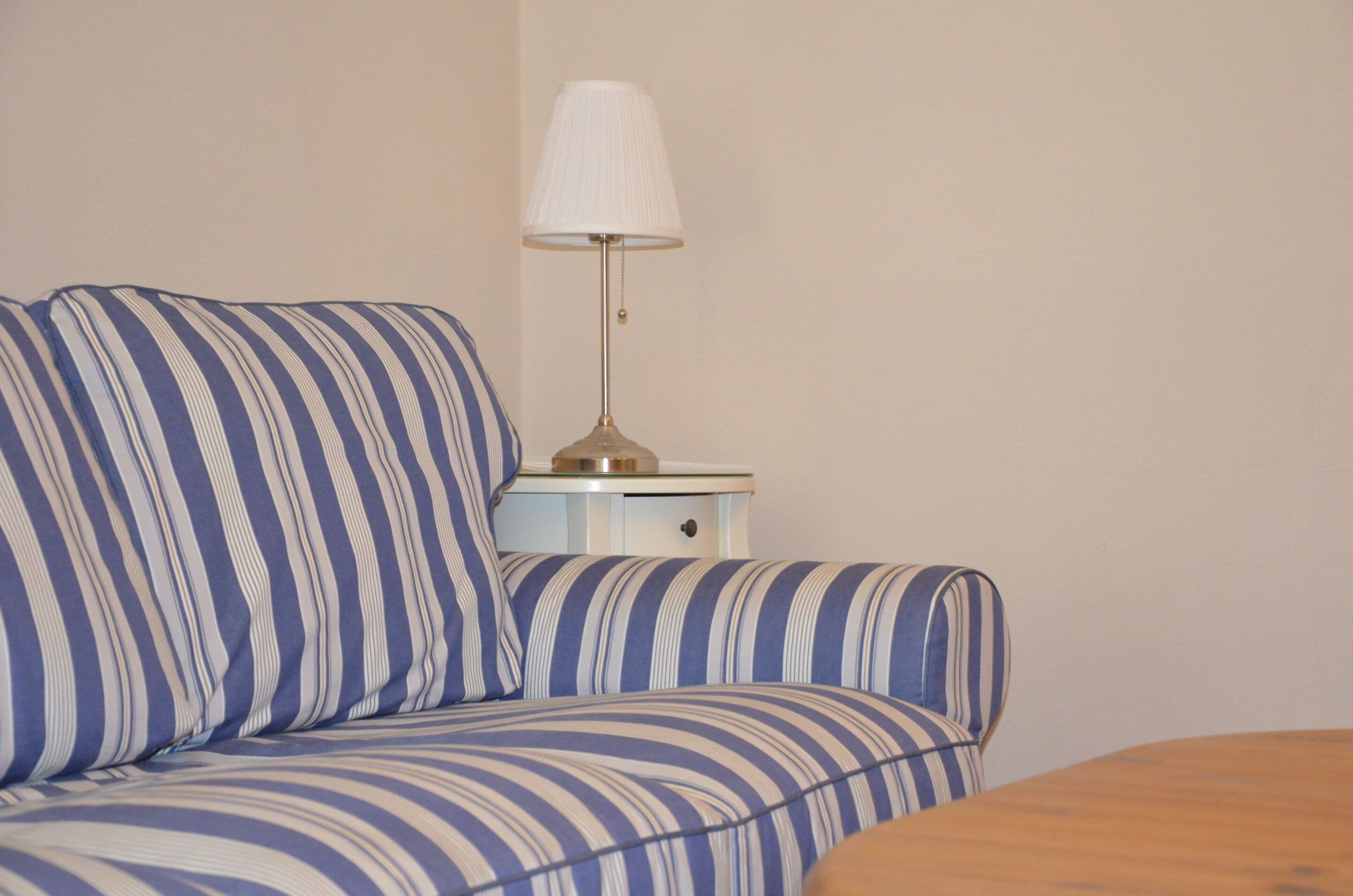 Un divano a righe e un comodino con una lampada in una stanza.