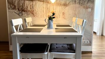 Een eettafel met witte stoelen en een vaas met bloemen.