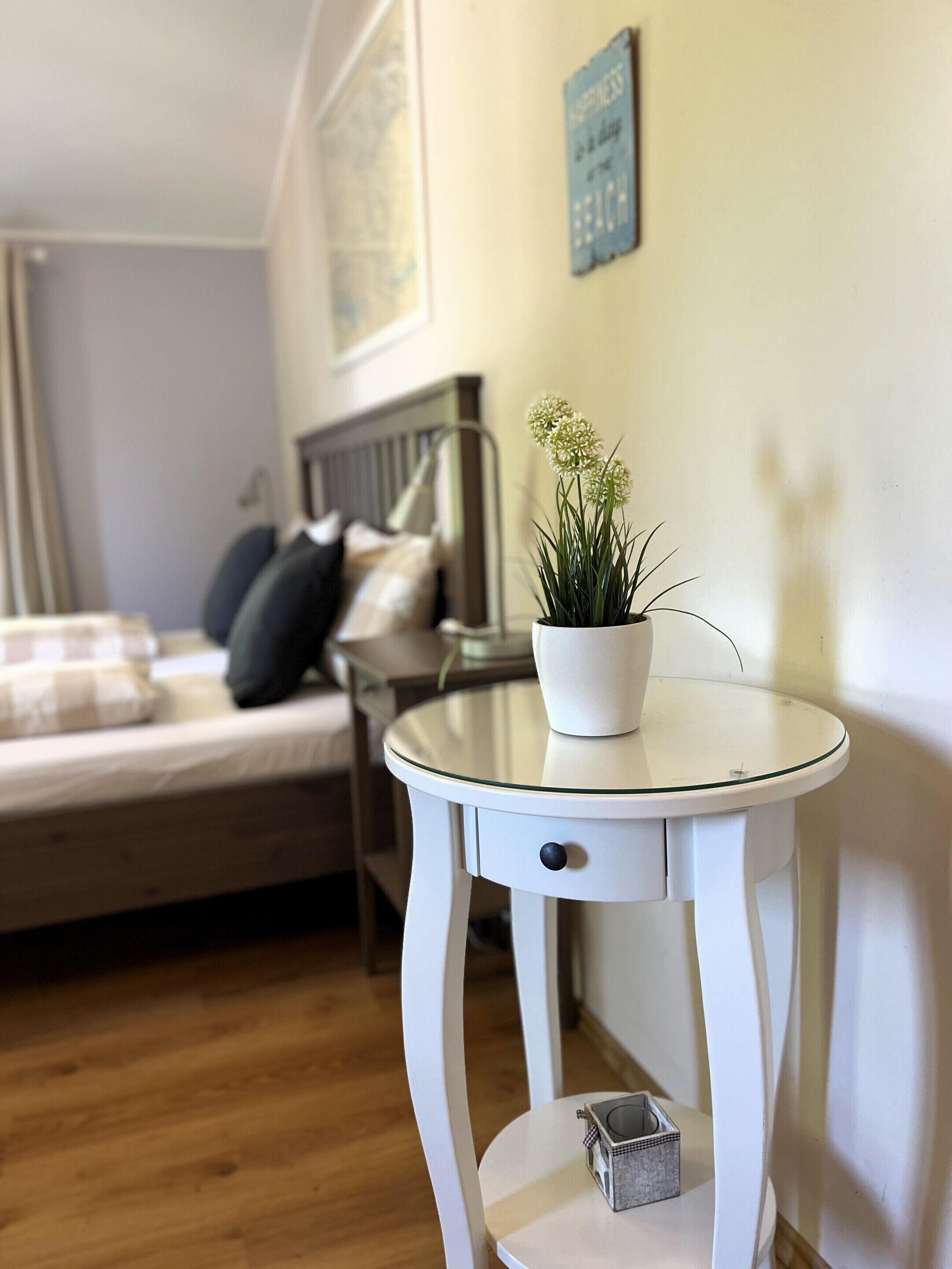 A neatly arranged bedroom with a bed, bedside table, and a small potted plant.