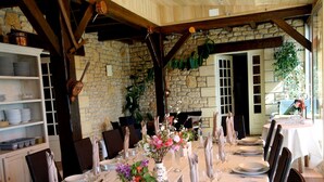 Una larga mesa de comedor preparada para una comida formal, con manteles blancos, cubiertos y copas.