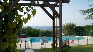 Un área de piscina con una pérgola, un cartel que indica que no se permite bucear y vistas del paisaje.