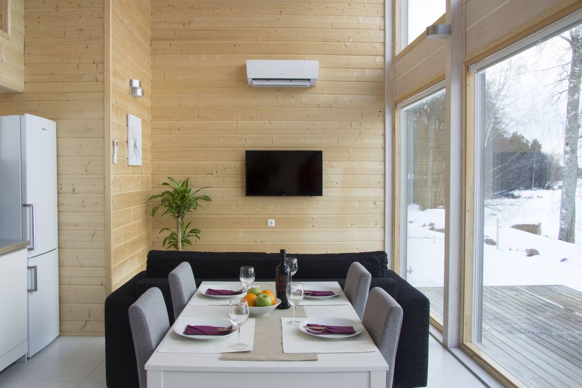Een moderne keuken met een inbouwkoelkast, een eethoek met een tafel voor vier personen, en een groot raam met uitzicht op een besneeerd landschap.