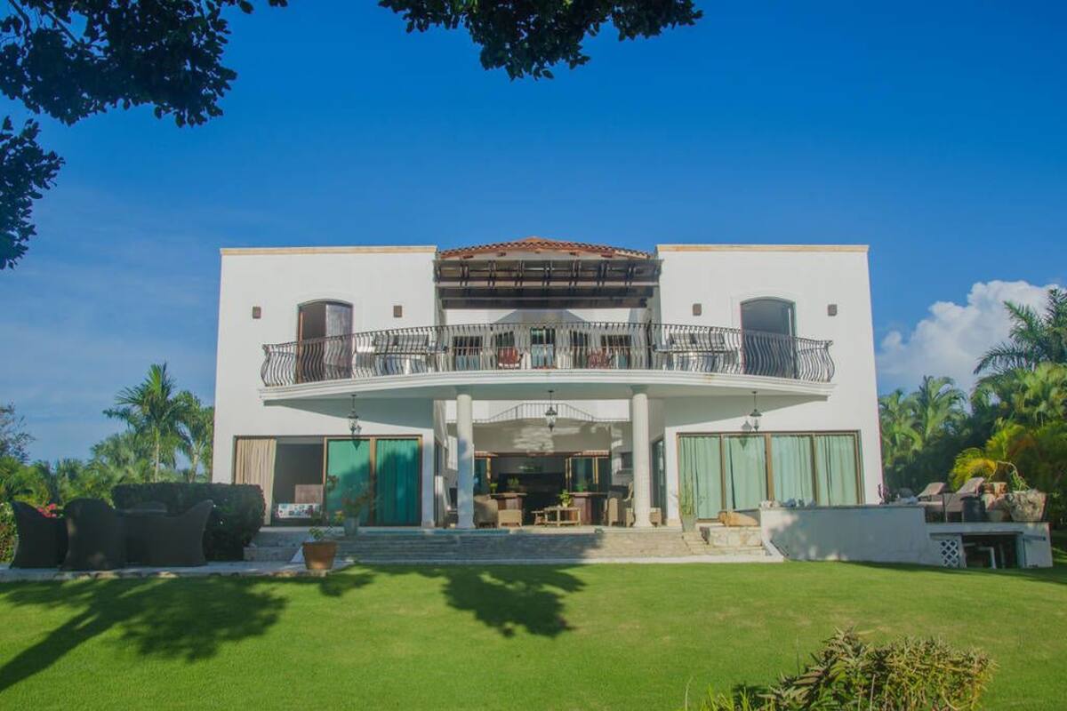Ein modernes, zweistöckiges Haus mit Balkon, überdachter Terrasse und gepflegtem Rasen.