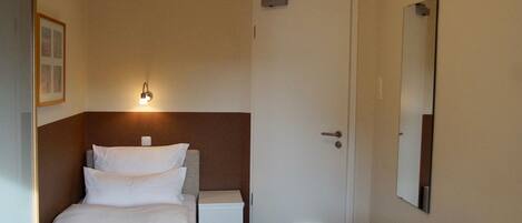 Une chambre d’hôtel avec un lit, une table de chevet et un miroir au mur.