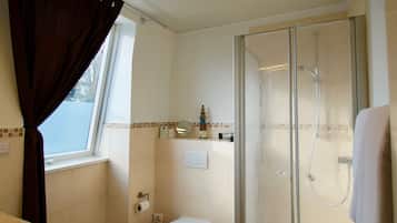 A bathroom with a glass-enclosed shower, a toilet, and a sink.