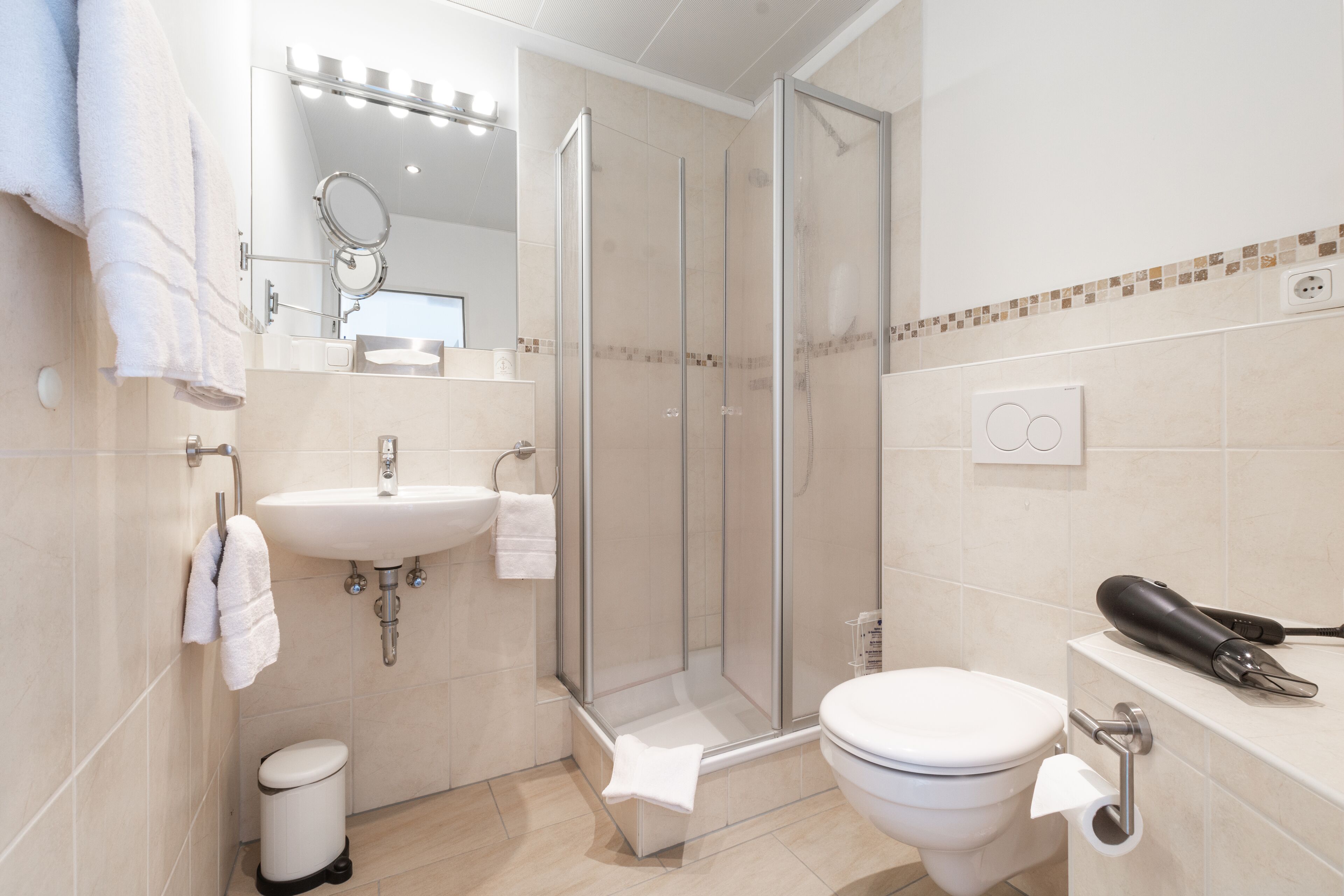 Un baño moderno con ducha de vidrio, lavamanos e inodoro.