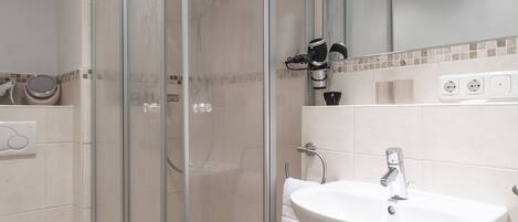 Un baño moderno con ducha acristalada, lavamanos blanco y retrete.