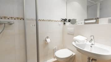 A modern bathroom with a glass shower enclosure, a white toilet, and a sink with a mirror above it.