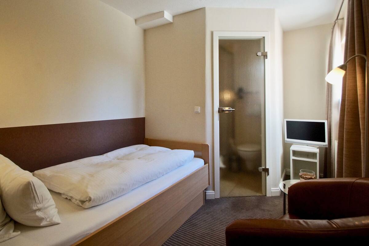 Ein Hotelzimmer mit Bett, Fernseher auf einem kleinen Tisch und einer Tür zum Badezimmer.