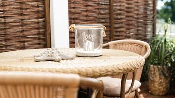 Uma mesa de vime com um castiçal de vidro rotulado 'Love Beach' e um par de tênis brancos sobre a mesa.
