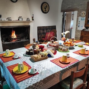 Un coin repas agrémenté d’une cheminée, une table mise avec des assiettes, des verres et une variété de plats.