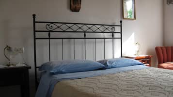 Una camera da letto con testiera in metallo, un letto con biancheria azzurra, un comodino con una lampada e una sedia rossa.