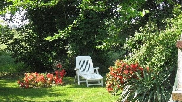 A garden with a white chair, lush greenery, and flowering plants. - Prisca (Ravenna)