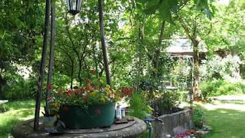 A garden with a stone fountain, potted plants, and a hanging lantern.