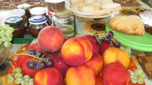 A table with a variety of fruits, bread, and jars of preserves. - Prisca (Ravenna)